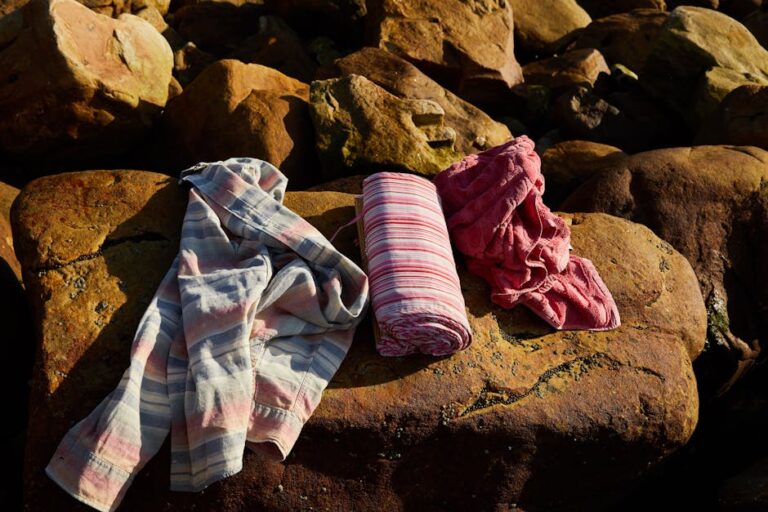 Vibrantly colored towels draped over sunlit rocks, capturing a warm outdoor setting.