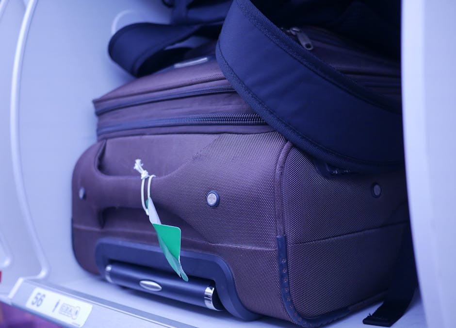 Close-up of luggage in an airplane's overhead compartment, showcasing travel essentials.