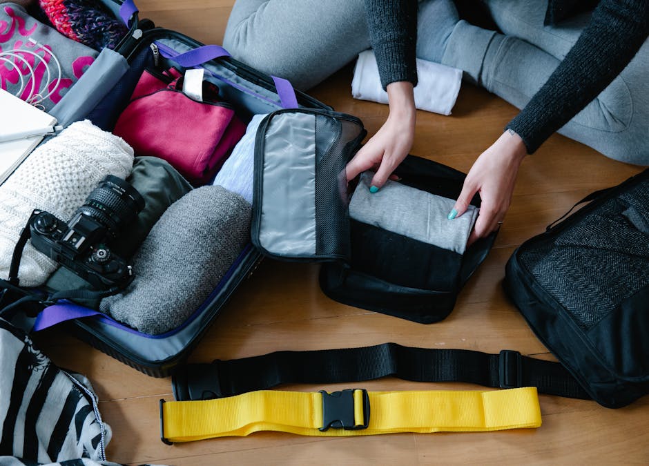 A woman arranging clothes and accessories into a suitcase, preparing for travel.