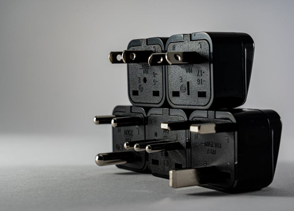 Close-up of black electrical adapters stacked on a gray background.