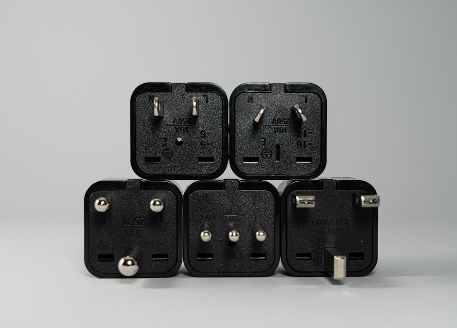 A collection of various black international power plug adapters for global electronics use.