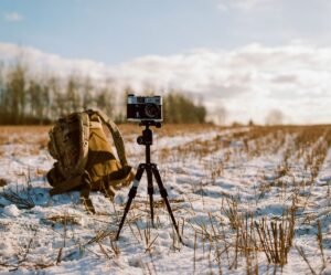 Cámara sobre trípode en un campo nevado al atardecer
