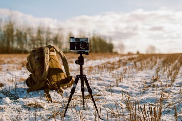 Cámara sobre trípode en un campo nevado al atardecer