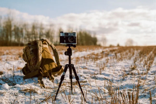 Cámara sobre trípode en un campo nevado al atardecer