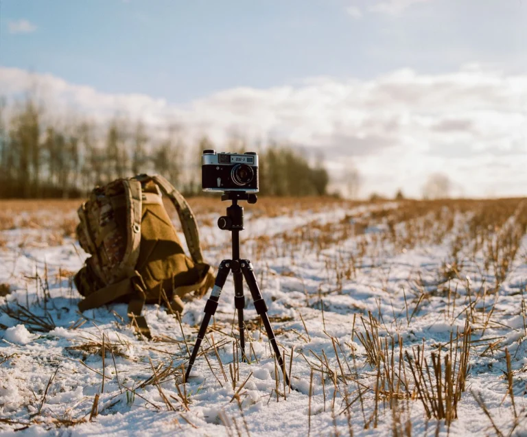 Cámara sobre trípode en un campo nevado al atardecer