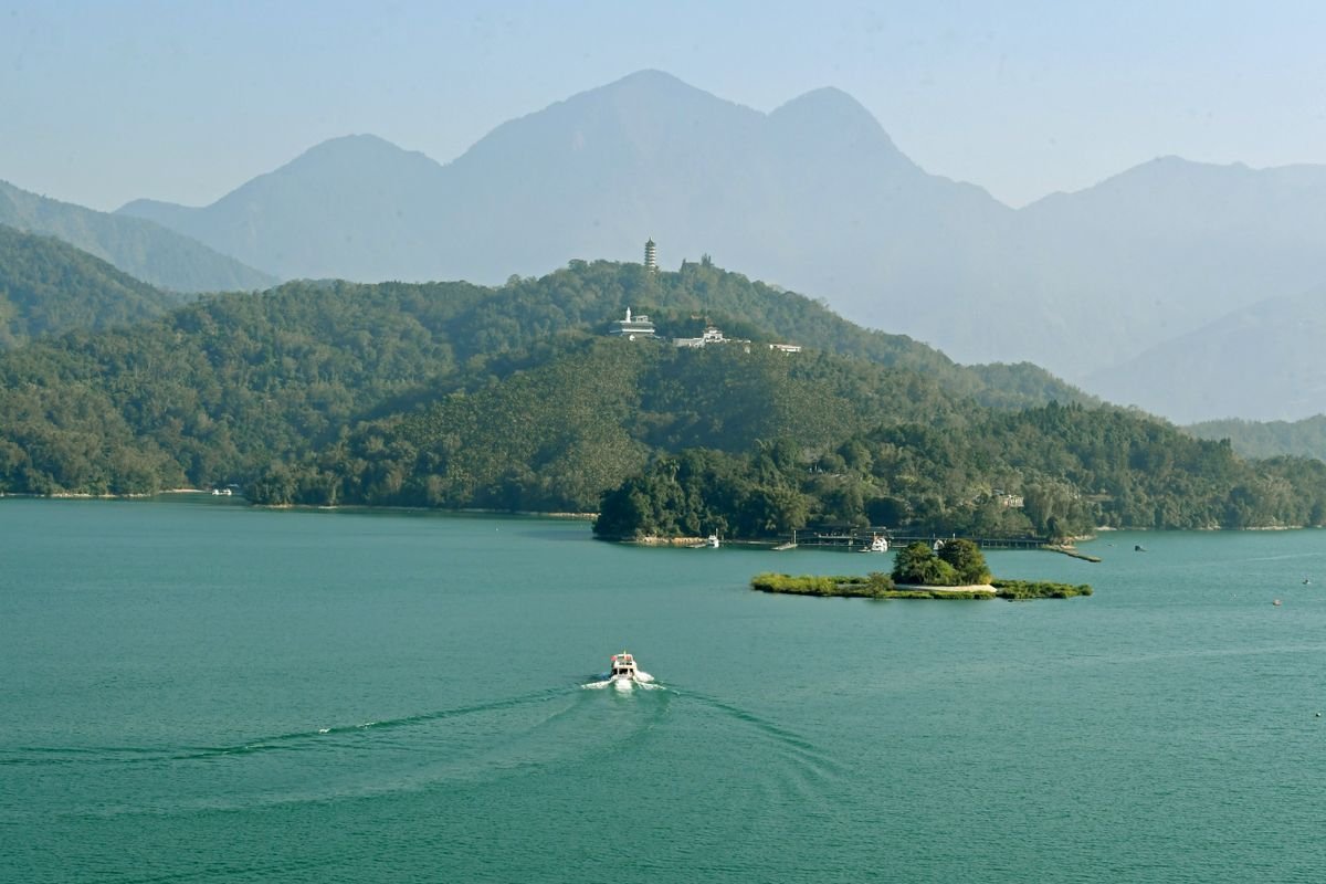 Vista aérea del Lago Sun Moon rodeado de montañas verdes con un barco navegando