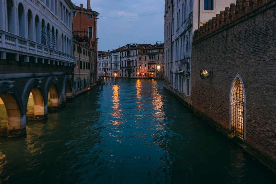 Callejuela estrecha con canal en Venecia al atardecer