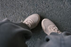Zapatillas blancas casuales fotografiadas sobre un pavimento texturizado, perfectas para temas de estilo de vida y moda.