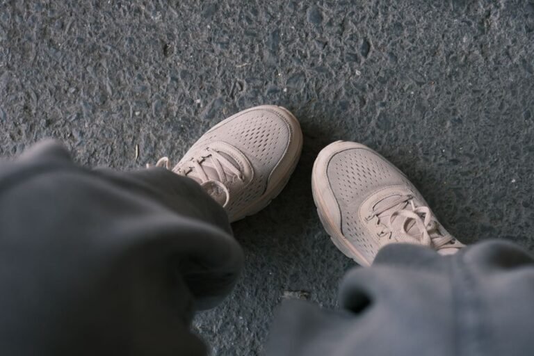 Zapatillas blancas casuales fotografiadas sobre un pavimento texturizado, perfectas para temas de estilo de vida y moda.