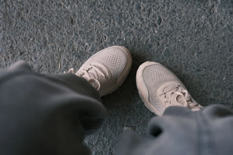Zapatillas blancas casuales fotografiadas sobre un pavimento texturizado, perfectas para temas de estilo de vida y moda.