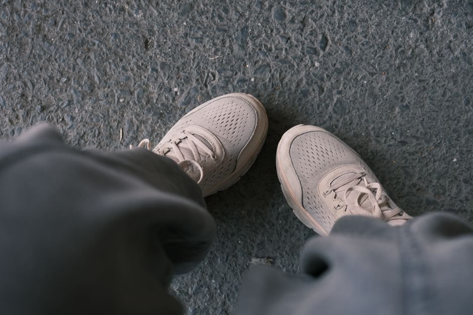 Zapatillas blancas casuales fotografiadas sobre un pavimento texturizado, perfectas para temas de estilo de vida y moda.
