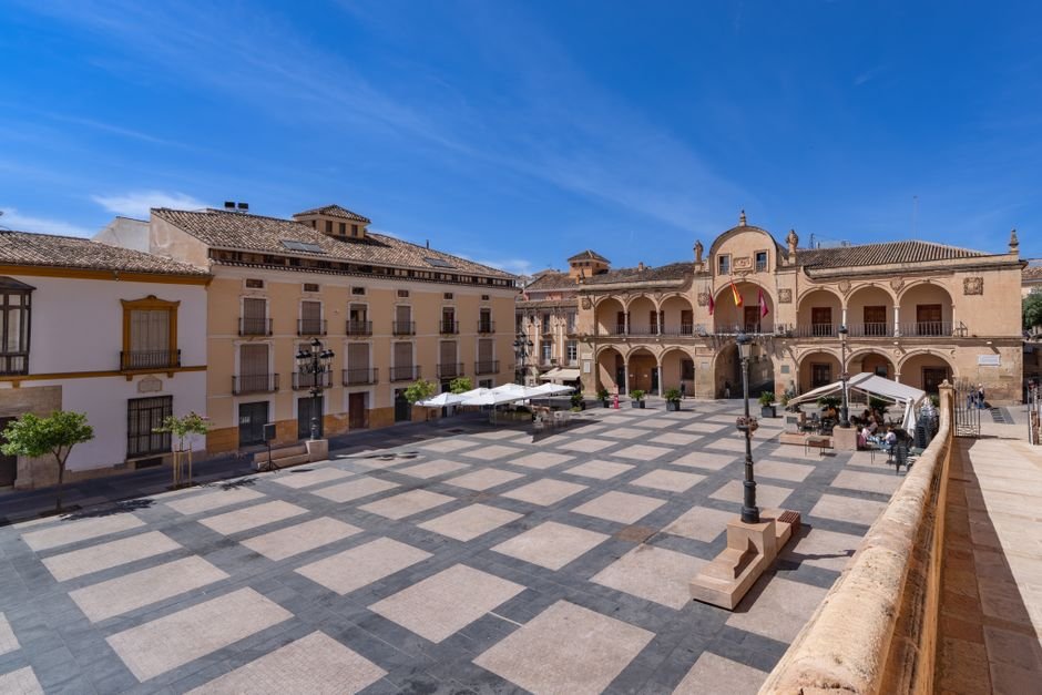 Plaza histórica de Murcia con arquitectura clásica y terrazas bajo un cielo azul