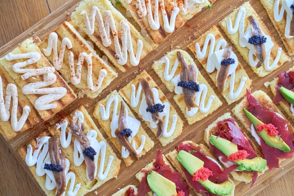 Selección de tapas variadas con anchoas, aguacate y caviar sobre rebanadas de pan