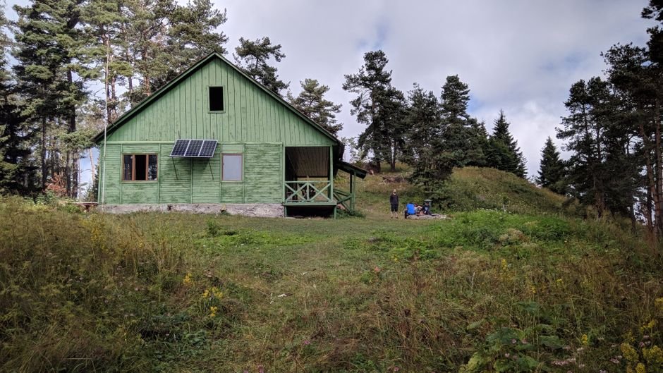 Encantadora casa de madera rural con paneles solares y vegetación exuberante