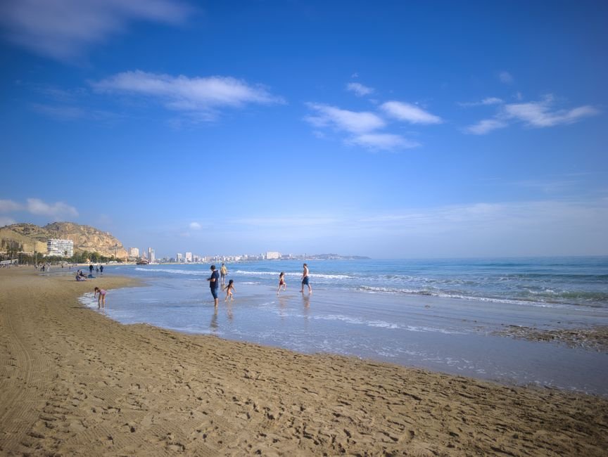 Vista panorámica de una familia jugando en la playa de Alicante bajo un cielo azul