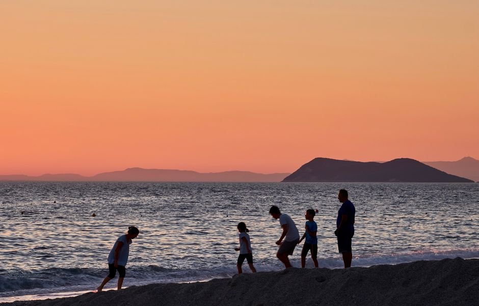 Familia disfrutando de un atardecer en la playa con cielos dorados