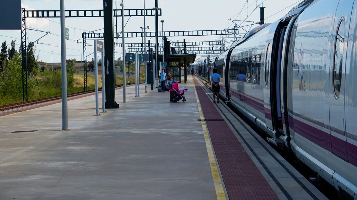 Viajeros junto a un tren de alta velocidad en una estación española