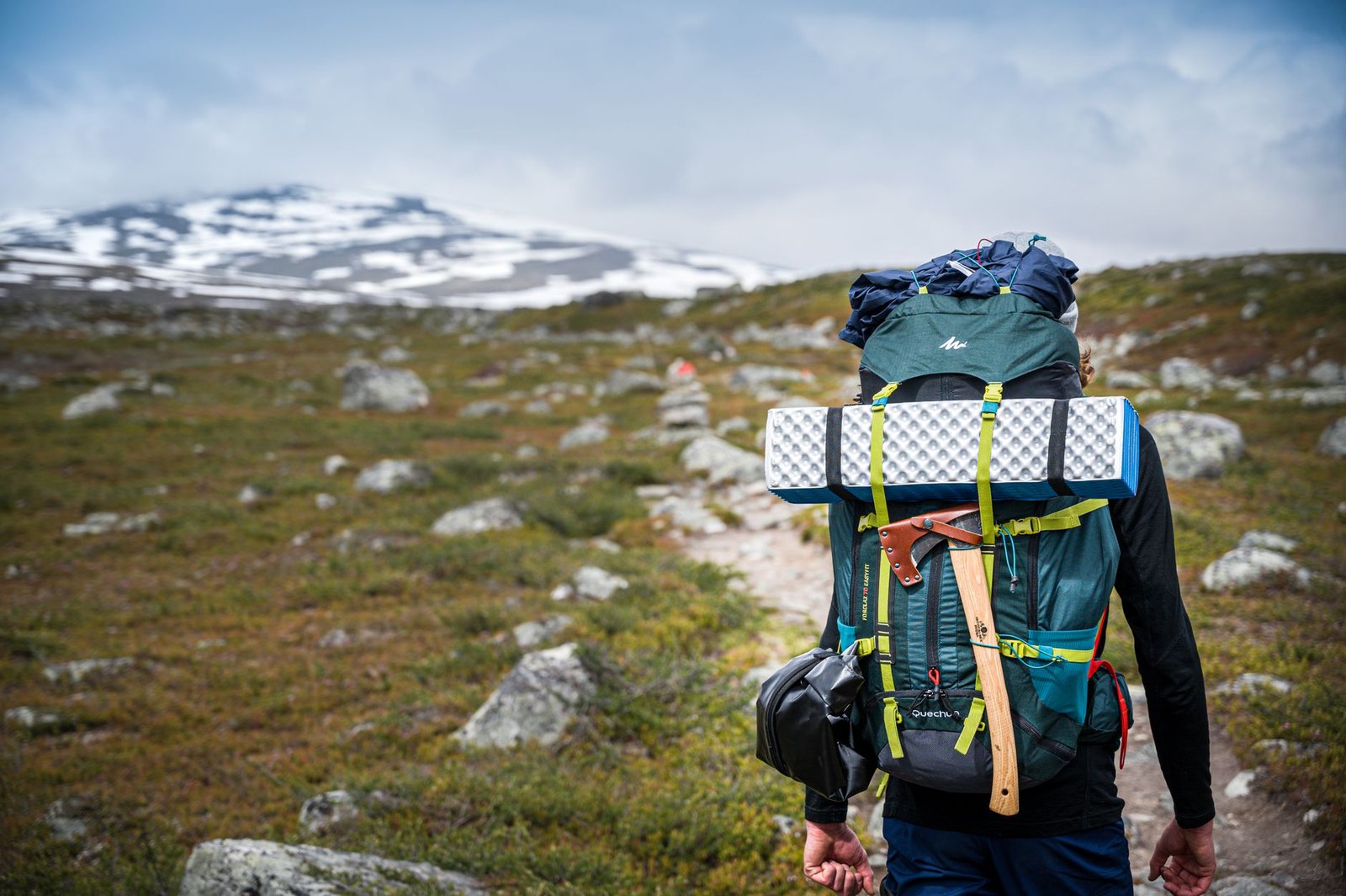 Viajero con mochila de senderismo caminando hacia las montañas