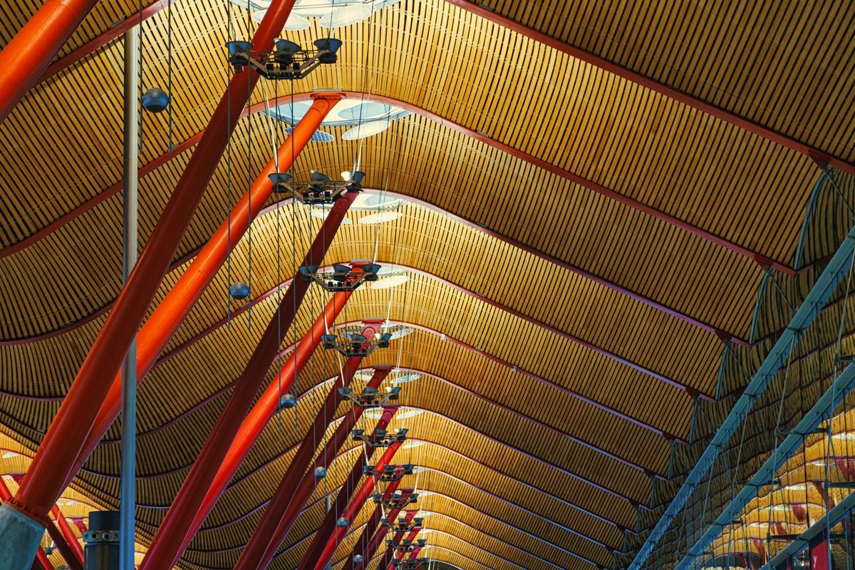 Interior del Aeropuerto de Madrid Barajas con su característico techo ondulado y postes de colores