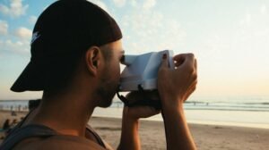 Persona haciendo una foto con cámara instantánea en la playa al atardecer durante un viaje