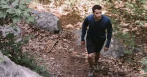Senderista con camiseta térmica de manga larga caminando por un sendero rocoso