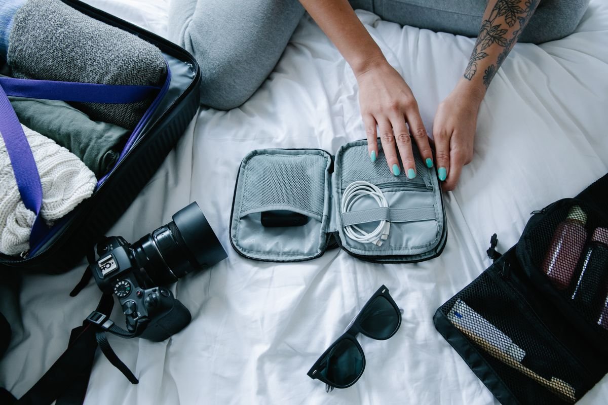 Viajera preparando la maleta con accesorios y electrónicos para un viaje improvisado