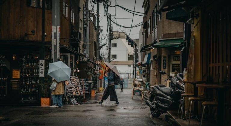 Personas con paraguas caminando bajo la lluvia en una calle urbana
