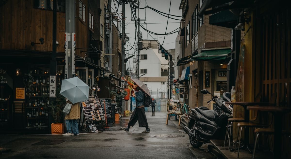 Personas con paraguas caminando bajo la lluvia en una calle urbana