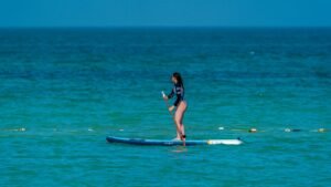 Mujer practicando paddle surf en un mar claro y tranquilo