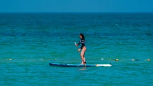 Mujer practicando paddle surf en un mar claro y tranquilo