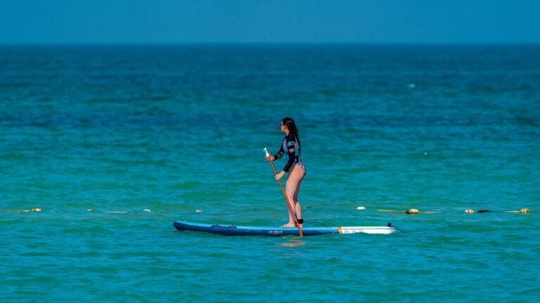 Mujer practicando paddle surf en un mar claro y tranquilo