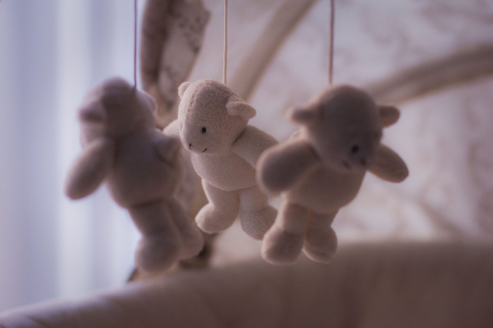 Cuna de bebé con móvil de peluche en una habitación luminosa