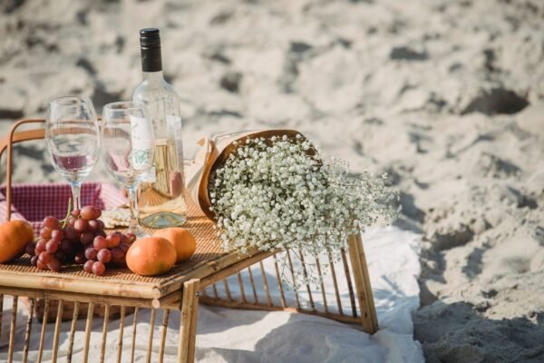 Picnic con nevera portátil en la playa: fruta, vino y bebidas frías sobre una mesa