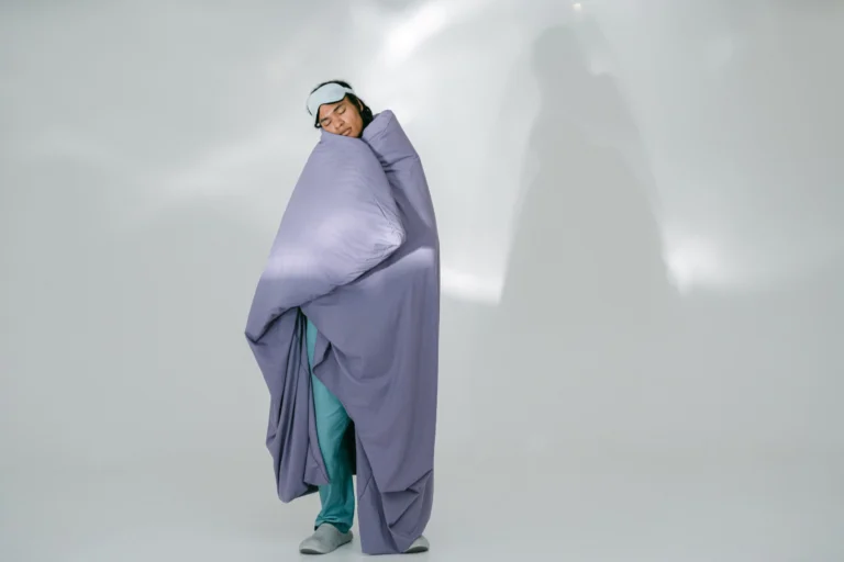 Persona envuelta en una manta de viaje con antifaz para dormir