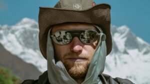 Hombre con gafas de sol y gorro en un paisaje de montaña nevada