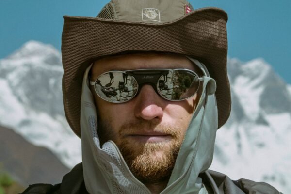 Hombre con gafas de sol y gorro en un paisaje de montaña nevada