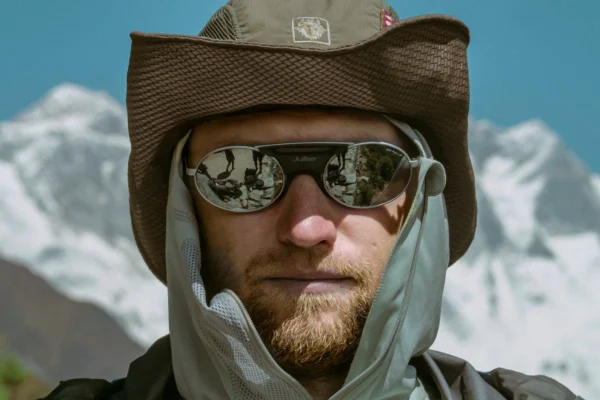 Hombre con gafas de sol y gorro en un paisaje de montaña nevada