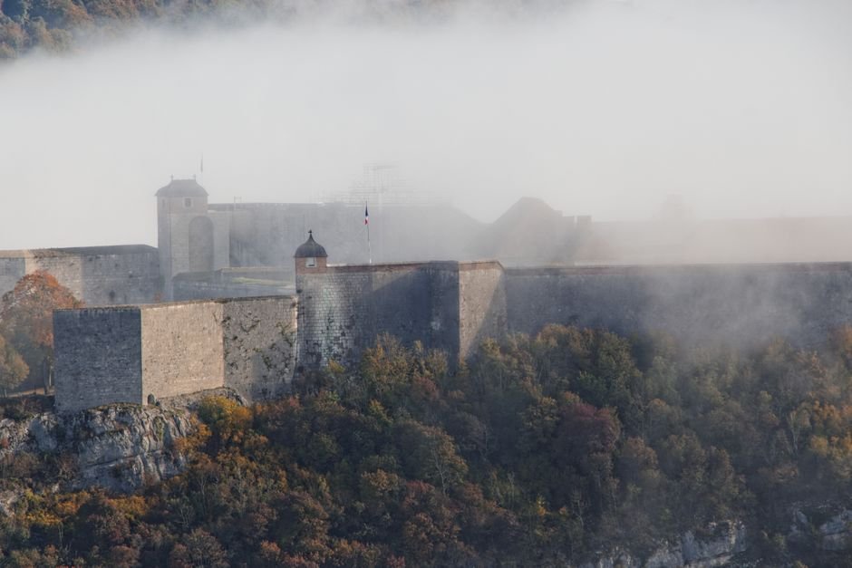 Castillo de piedra entre niebla y arboles otonales