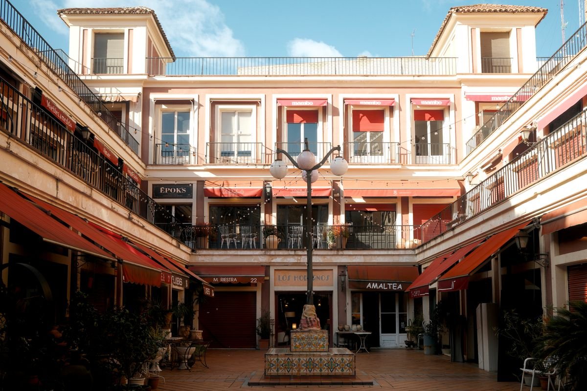 Plaza soleada con terraza y fuente en el centro histórico de Murcia