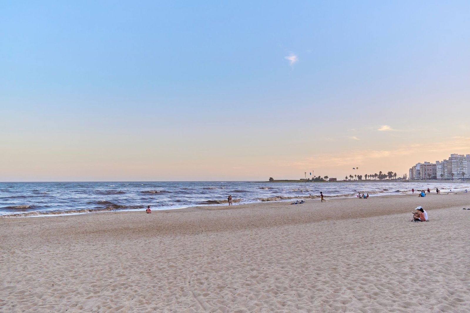 Playa tranquila al atardecer con el horizonte al fondo, un rincón que aún respira paz en pleno agosto
