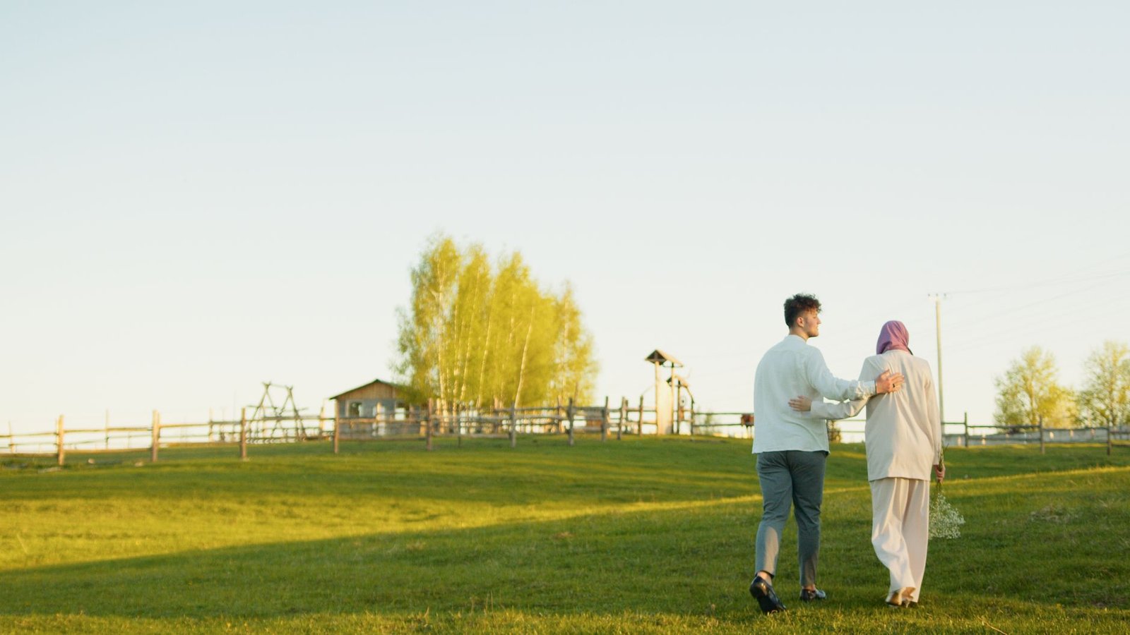 Pareja caminando de la mano por un campo soleado, la escapada rural como alternativa al turismo masivo