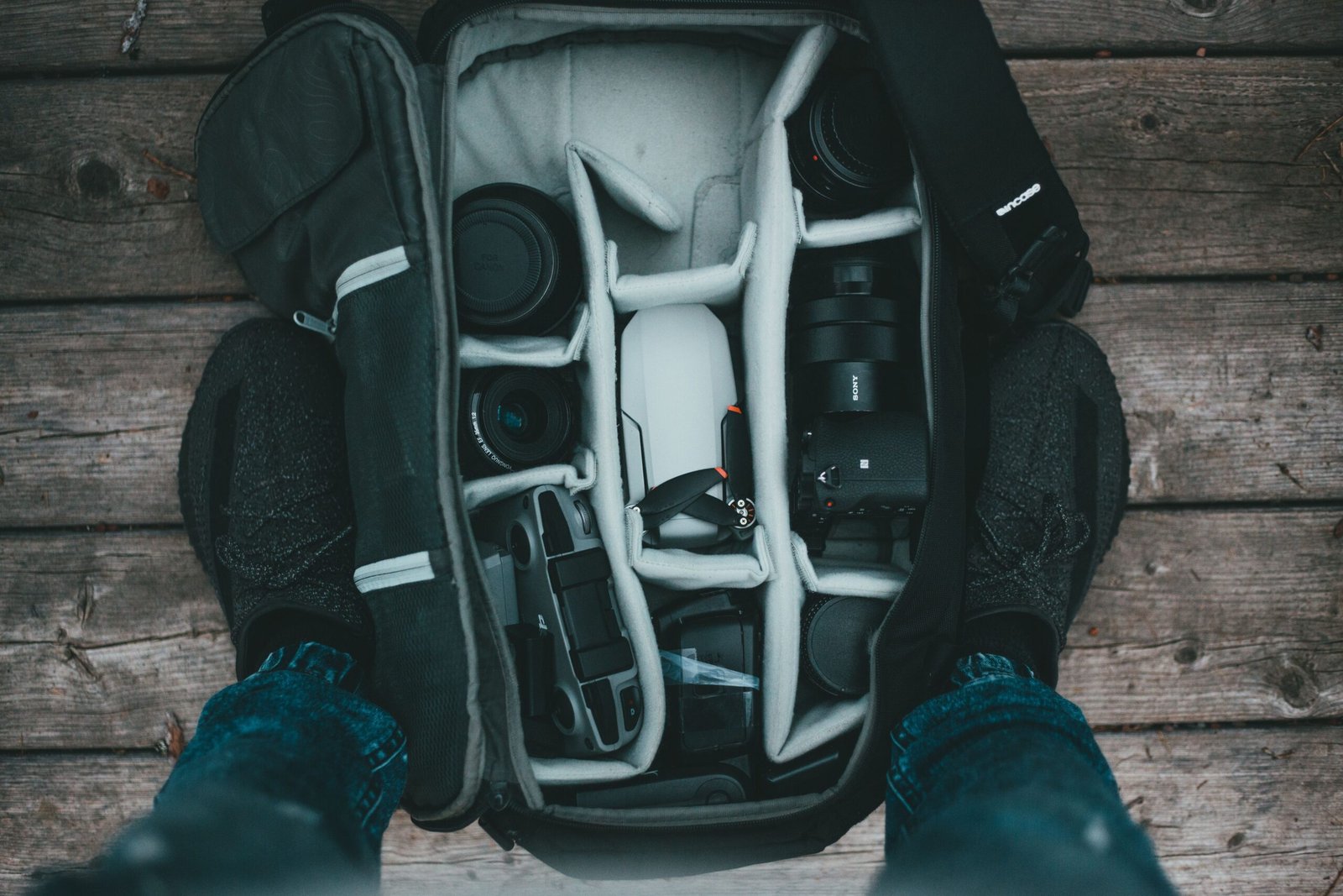 Mochila para cámara con equipo fotográfico organizado en su interior sobre fondo de madera