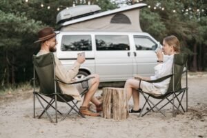 Pareja junto a su autocaravana en la naturaleza, preparando el viaje con nevera de compresión a bordo