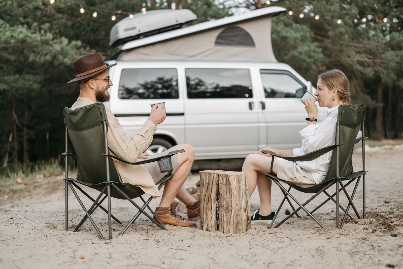 Pareja junto a su autocaravana en la naturaleza, preparando el viaje con nevera de compresión a bordo