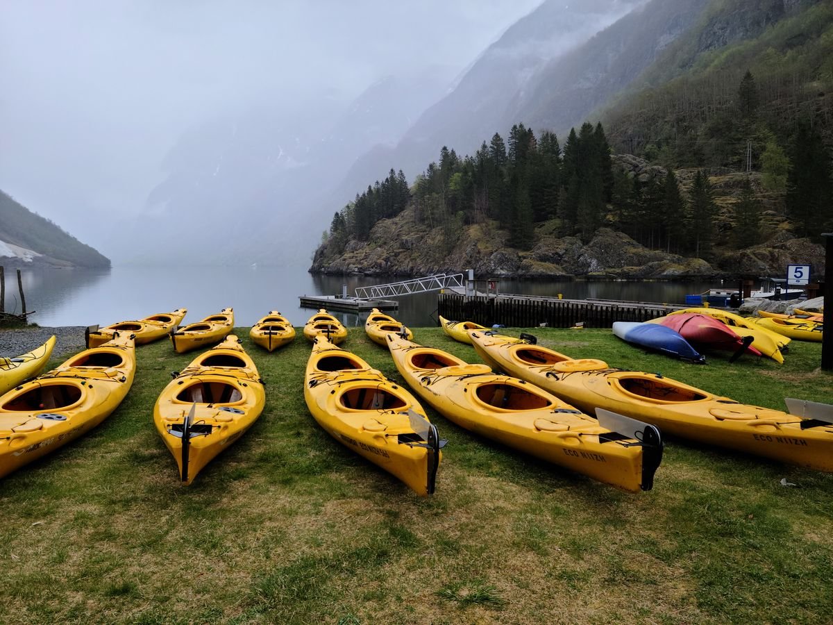 Kayaks amarillos alineados en la orilla de un fiordo noruego listos para zarpar