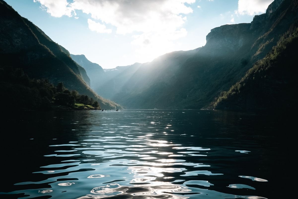 Fiordo noruego iluminado por el sol con agua brillante y montañas majestuosas