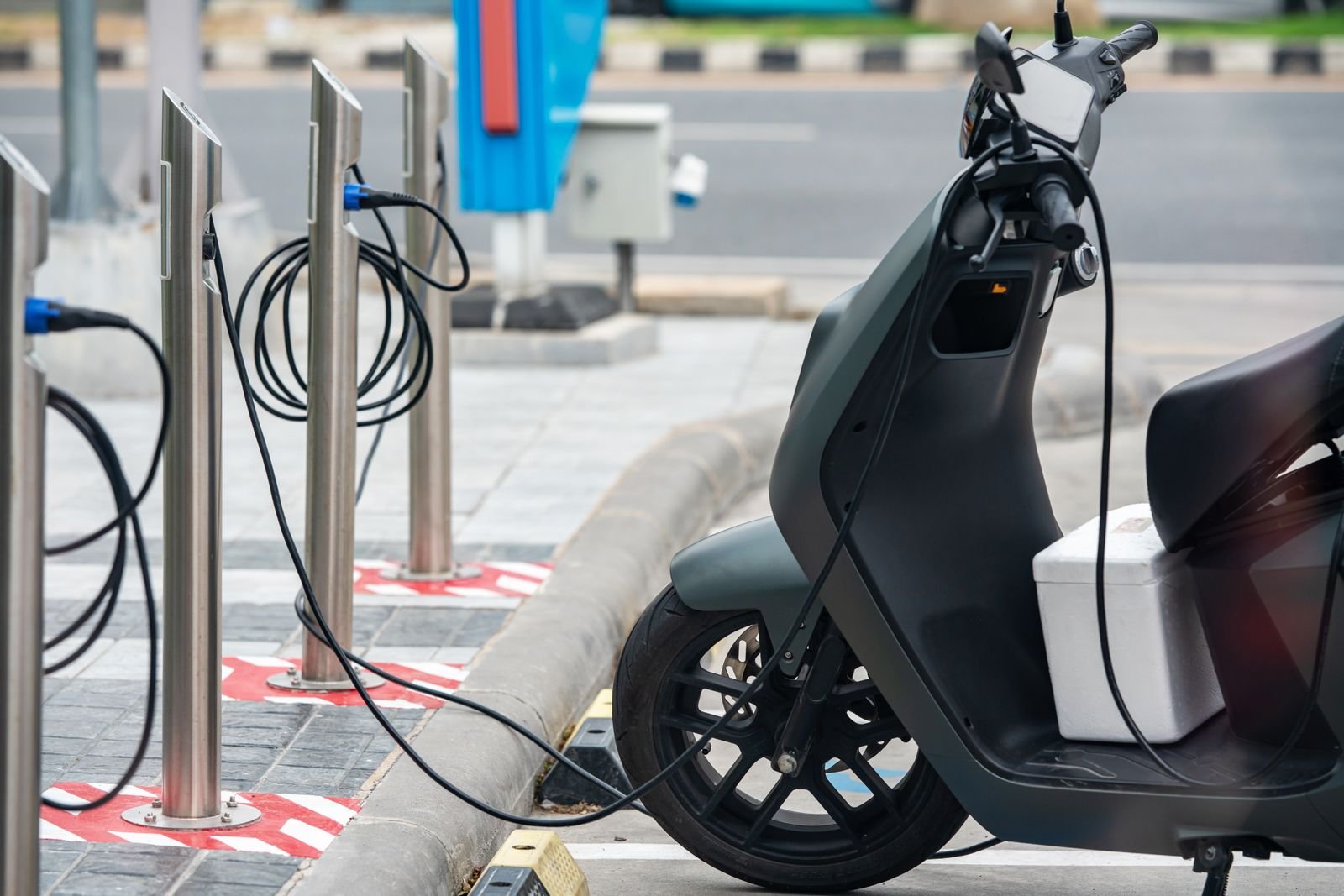 Patinete eléctrico enchufado a un punto de carga en la ciudad