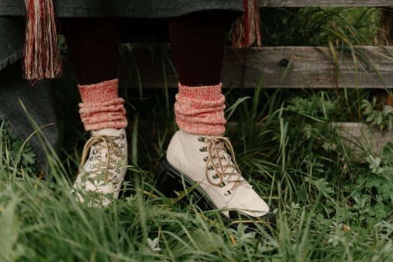 Botas de senderismo blancas con calcetines rojos sobre hierba verde