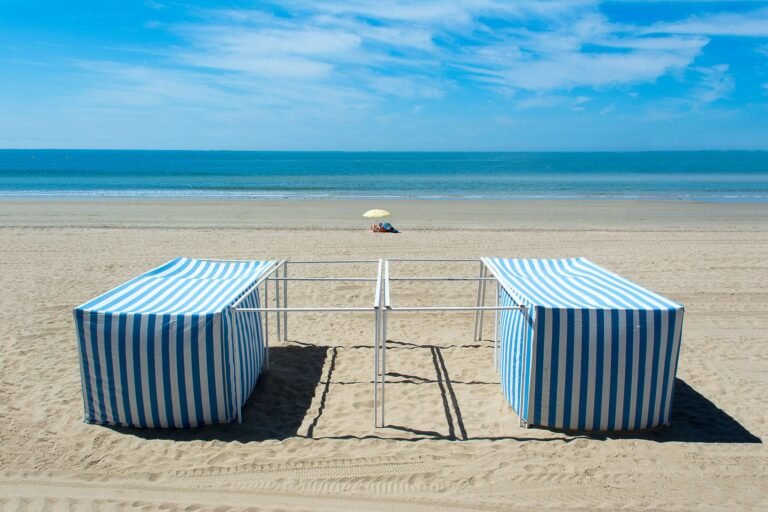 Sombrilla y tiendas de playa a rayas montadas sobre la arena junto al mar