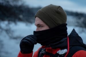 Excursionista en la montaña nevada con una braga de cuello de forro polar subida hasta la nariz